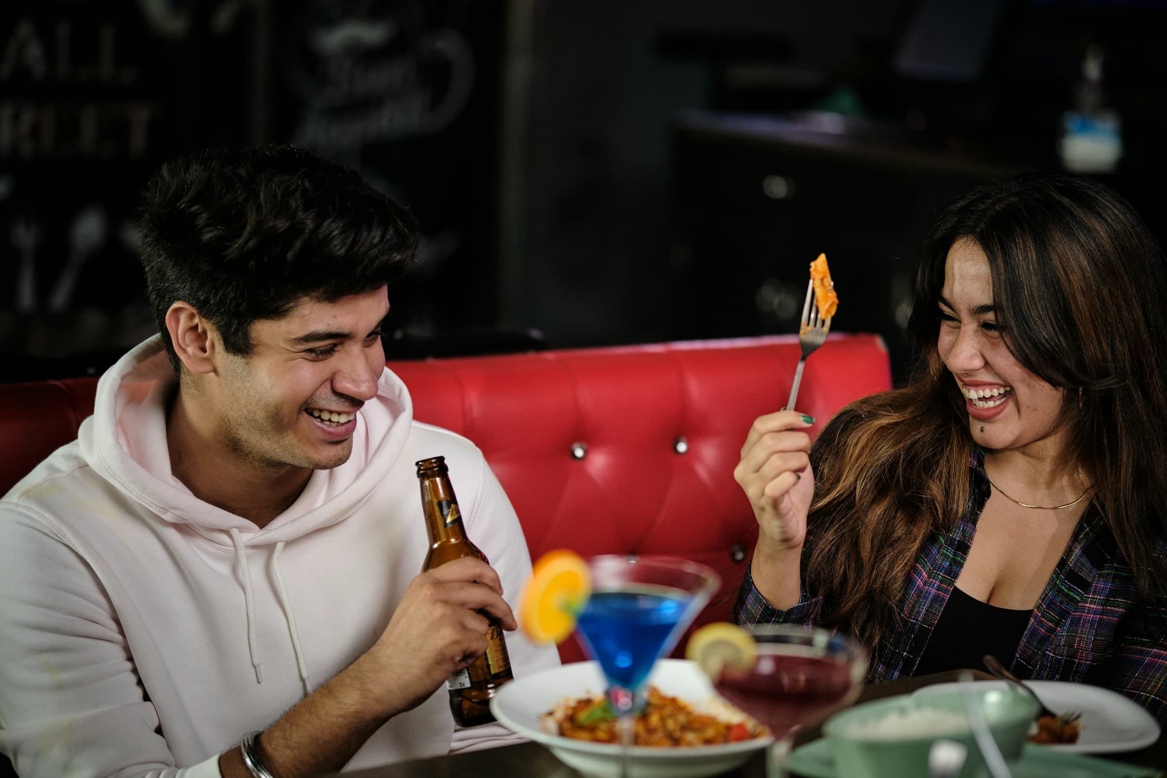 A couple laughing together over dinner and drinks